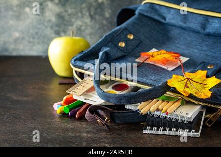 Zurück zum Schulkonzept. Schulzubehör mit blauem Rucksack auf dem Tisch. Freier Speicherplatz für Ihren Text. Stockfoto