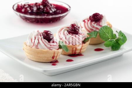 Hausgemachte Törtchen mit Frischkäse, Kirschmarmelade und Minze Stockfoto