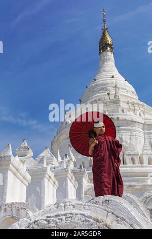 Junge Novizin buddhistischer Mönch holding Sonnenschirm am Myatheindan Pagode (auch als Hsinbyume Pagode bekannt), Mingun, Myanmar (Burma), Asien im Februar Stockfoto