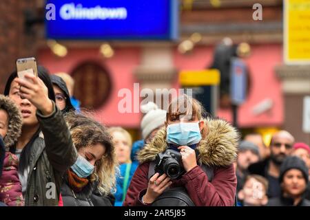 London, Großbritannien. Januar 2020. Mitglieder der Öffentlichkeit, die Facemasken trägt, erwarten Drache- und Löwen-Tänzerinnen und traditionelle kostümierte Charaktere, die im Rahmen der chinesischen Neujahrsfeier in Chinatown an einer Parade teilnehmen, um das Jahr der Ratte zu feiern. Das chinesische Neujahr in der Hauptstadt zieht hunderttausende Londoner und Touristen an und ist die größte solche Feier außerhalb Asiens. Die diesjährige Veranstaltung findet im Schatten eines Ausbruchs des Coronavirus im chinesischen Wuhan statt, das bisher 56 Menschen das Leben forderte. Kredit: Stephen Chung / Alamy Live News Stockfoto