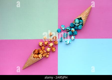 Popcorn Herausspritzen von Waffel Eiswaffel auf pastel farbigen Hintergrund. Blau und Karamell Popcorn auf einem Kegel Füllhorn der Ansicht von Oben hell Hipster Stockfoto