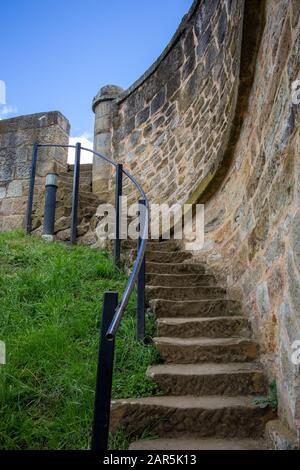 Ein vertikaler Schuss einer Treppe neben einer alten Ziegelmauer Stockfoto