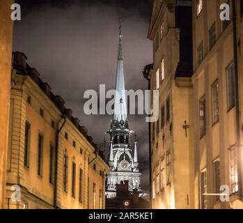 Selektive Fokusaufnahme eines Kirchturm bei Nacht mit Gebäuden Im Vordergrund Stockfoto
