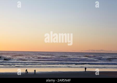 Landschaft mit Familien, die den Sonnenuntergang am Cannon Beach, Oregon, USA, genießen Stockfoto