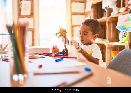 Schöne afrikanische amerikanische Kleinkind spielen mit Dinosaurier Spielzeug auf dem Schreibtisch im Kindergarten Stockfoto