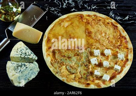 Pizza mit verschiedenen Käsesorten auf einer dunklen Holzoberfläche. Stockfoto