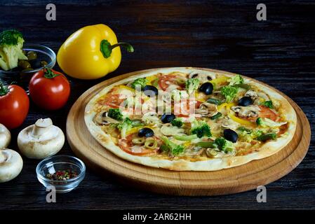 Pizza mit Gemüse auf einer dunklen Holzoberfläche. Stockfoto