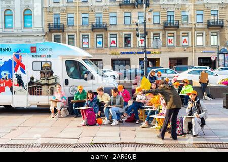 Sankt PETERSBURG, RUSSLAND - 11. JULI 2019: Lehrer, der einer Gruppe von Kunstschülern erklärt, die in Gostiny dvor, Bus mit HIV-Mobilgerät, auf der Straße skizziert haben Stockfoto