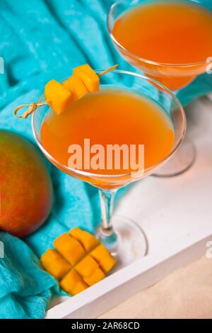 Eine Brille tropischer exotischer Mango-Saft-Cocktailgetränke auf dem weißen Tablett. Tripical Beach Picknickkonzept Stockfoto