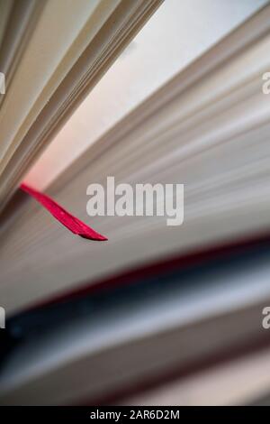Antikbuch auf einer Seite mit einem roten Bandlesezeichen geöffnet Stockfoto