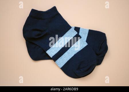 Niedrig ansteigende Socken für Damen. Dunkelblaue Socken mit zwei grauen Streifen auf orangefarbenem Hintergrund Draufsicht. Ein Paar neue Socken aus Baumwolle für den Sport. Stockfoto