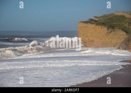 Hohe weiße Brecher von einem Kanal stürmen den Strand und die Sandsteinfelsen am Hive Beach, in der Nähe von West Bay, Dorset, Januar Stockfoto