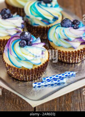 Festlicher Cupcake auf Holzhintergrund mit heller Creme und Blaubeere im Kerzenrustikalen Stil, Süßwarenbar und süßer Bar. Stockfoto