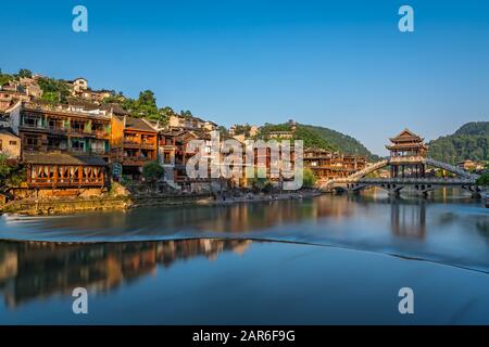 Feng Huang, China - August 2019: Lange Zeit ist die Steinbrücke über den Fluss Tuo Jiang und Holzhäuser in der alten Altstadt von Fenghuang bekannt Stockfoto