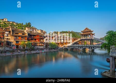 Feng Huang, China - August 2019: Lange Zeit ist die Steinbrücke über den Fluss Tuo Jiang und Holzhäuser in der alten Altstadt von Fenghuang bekannt Stockfoto