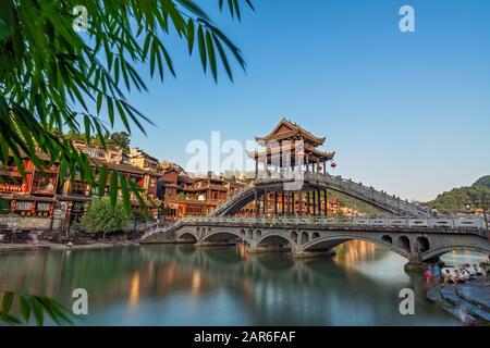 Feng Huang, China - August 2019: Lange Zeit ist die Steinbrücke über den Fluss Tuo Jiang und Holzhäuser in der alten Altstadt von Fenghuang bekannt Stockfoto