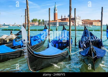 Liegeplatz mit Gondeln in der Nähe des Markusplatzes in Venedig, Italien. Lagune von Venedig. San Giorgio Maggiore im Hintergrund. Die Gondel ist ein traditionelles r Stockfoto