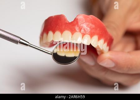 Zahnprothese in der orthodentistischen Zahnarzthand, Überprüfung mit Spiegel Stockfoto