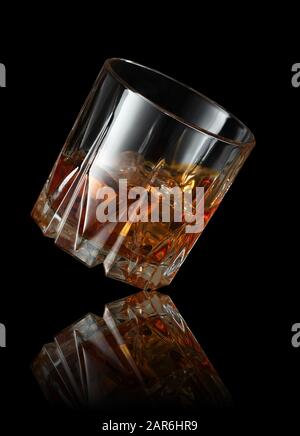 Fallende Glas Whisky mit Eiswürfel auf schwarzem Hintergrund Stockfoto