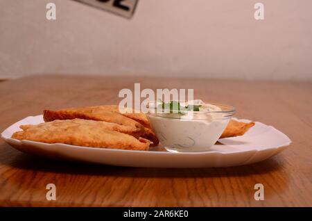 Usbekische Osttatarische Küche, Käserei mit Fleisch und Suluguni-Käse auf einem weißen Teller mit Gemüse und Gemüse auf einem Holztisch. Stockfoto