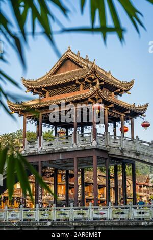 Feng Huang, China - August 2019: Traditionelle Pagode, wie sie auf der Steinbrücke über den Fluss Tuo Jiang gebaut wird, und Holzhäuser in alter Zeit Stockfoto