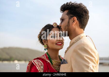 Porträt des jungen indianischen Paares, das in bunten Kleidern in der Nähe des Pichola-Sees in Udaipur, Rajasthan, Indien, verheiratet sein soll. Stockfoto