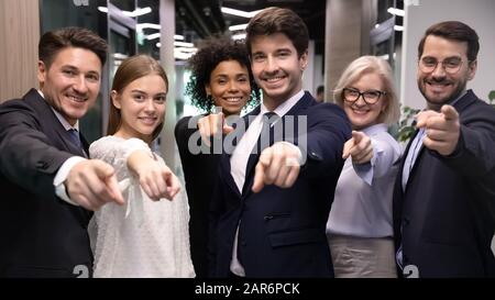 Glückliche, unterschiedliche Altersgruppen, multirassische Geschäftsleute, die mit den Fingern auf die Kamera zeigen. Stockfoto