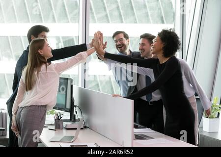 Überglücklich gaben verschiedene Mitarbeiter hohe fünf und feierten den erfolgreichen Abschluss des Projekts. Stockfoto