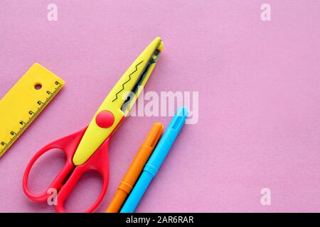 Schere, Lineal und Flusskrebse auf einem rosafarbenen Hintergrund. Kreativer, modischer, minimalistischer Arbeitsplatz in der Schule oder im Büro mit gelbem Zubehör für Handarbeit Stockfoto