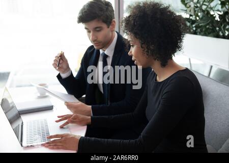 Junge afroamerikanische Geschäftsfrau, die am Computer arbeitet, Kontrolleur prüft Dokumente. Stockfoto