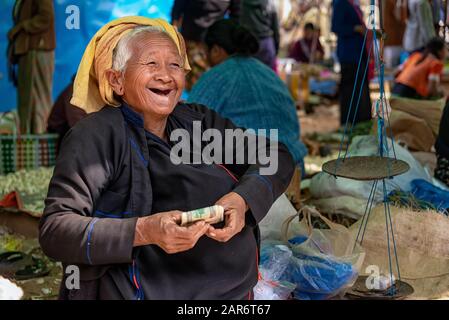Phaung Daw, Myanmar - 28. Dezember 2019: Lächelnde ältere Pa'o-Frau auf dem Phaung Daw Oo Market mit Geld eines letzten Verkaufs Stockfoto