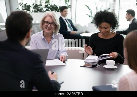 Lächelnde, unterschiedliche Altersgruppen, multirassische Geschäftsleute treffen sich im modernen Büro. Stockfoto