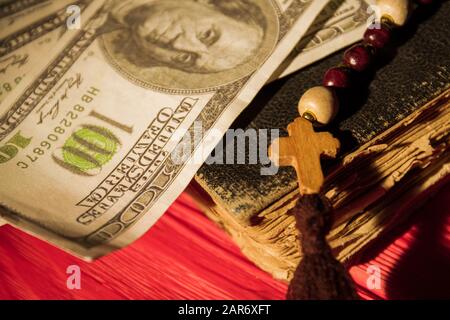 Nahaufnahme von altem Buch, Holzkreuz an Perlenkette und Geld. Stockfoto