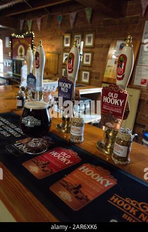 Eine halbe Pint Bier gegen eine Reihe von Bierpumpen in einem englischen Pub in der 1849 gegründeten Hooks Norton Brewery im Dorf Hook Stockfoto