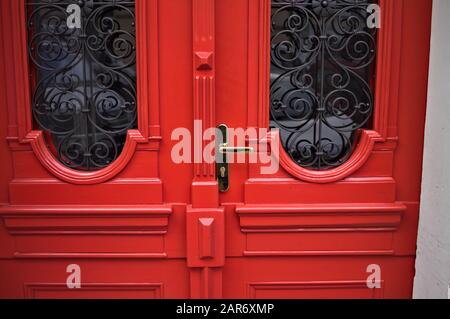 Rote Holztür mit zwei Fensterbrillen und schwarzen Dekorationen (Prag, Tschechien, Europa) Stockfoto