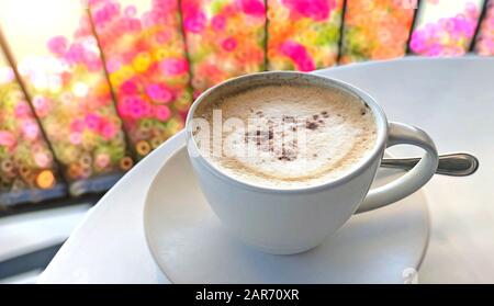 Cappuccino-Kaffee wird auf einem weißen Tisch in einem Café serviert Stockfoto