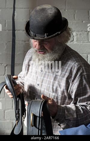 Drayman, Roger Hughes wählt die Zügel aus, einen Teil der Shire Pferdekarre Kabelbäume im stabilen Tackenzimmer in der familieneigenen Hooks Norton Brewery gefunden Stockfoto