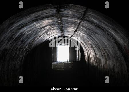 Spoky, creepy bogenförmige Passage in einem verlassenen Gebäude, alte militärische Fort Innenbetonkonstruktion, städtische Erkundung Stockfoto