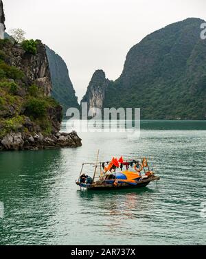 Traditionelles vietnamesisches Korakelboot mit Kalksteinkarstfelsen bei nebeligem Wetter, Halong Bay, Vietnam, Asien Stockfoto