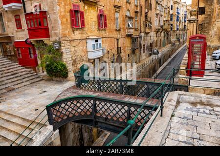 Altstadt von Il-Belt Valletta auf Malta, traditionelle Häuser, Fußgängerbrücke über die Liesse Straße, Bridge Bar und rote Telefonzelle Stockfoto