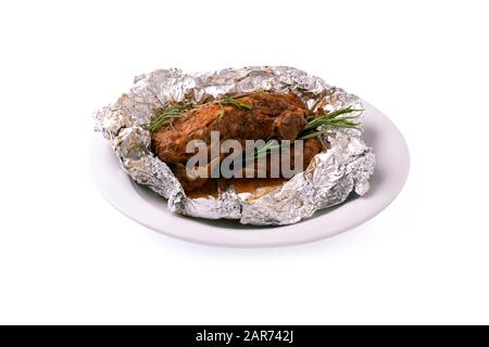 Platte mit gebackenem Lamm mit Rosmarin in Folie, isoliert auf weißem Hintergrund Stockfoto