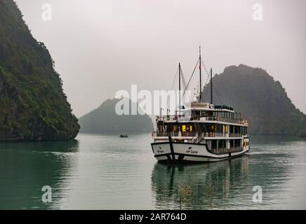 Touristenschiff Azalea, das in der Abenddämmerung bei nebeligem Wetter vor Anker lag, Halong Bay, Vietnam, Asien Stockfoto