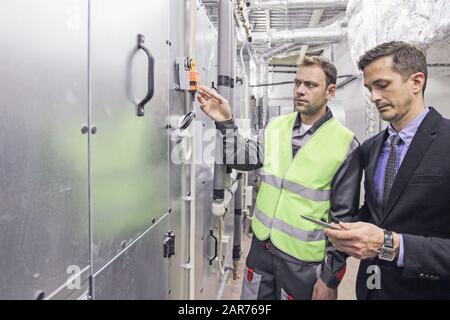 Elektriker, die in der elektrischen Schranksteuerung arbeiten, Schaltanlagenbetreiber Stockfoto