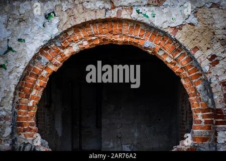 Großer Ziegelbogen eines verlassenen Wohnhauses und dunkles Zimmer im Inneren Stockfoto