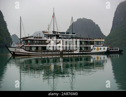 Tourist Azalea Kreuzfahrtschiff & Tender vor der Dämmerung bei nebeligem Wetter verankert, Halong Bay, Vietnam, Asien Stockfoto