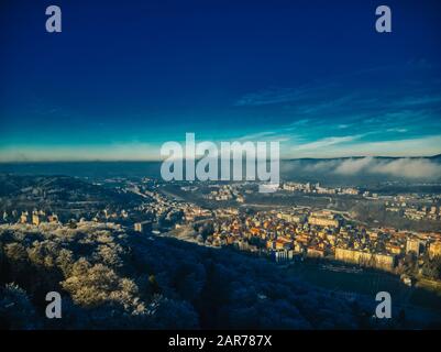 Luftaufnahme des Kiefernwaldes am kalten Wintermorgen mit frühwarmer Sonneneinstrahlung in die europäische Stadt Stockfoto