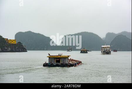 Kreuzfahrtschiffe und Frachtkähne bei nebeliger Witterung mit Kalkkarstfelsen, Halong Bay, Vietnam, Asien Stockfoto