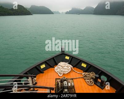 Bug des Kreuzfahrtschiffes, das zu Kalksteinkarstfelsen in Nebel, Halong Bay, Vietnam, Asien führt Stockfoto