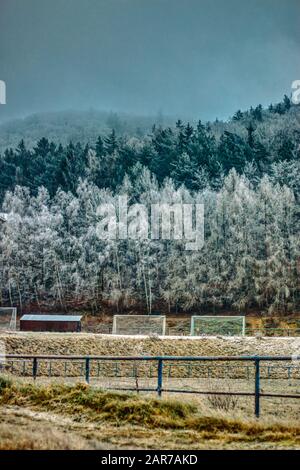 Winter-Fußballfeld mit verfrosteten Bergen im Hintergrund und Toren Stockfoto