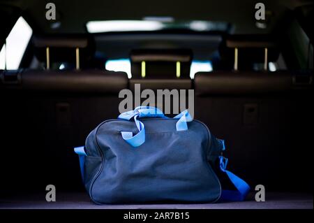Die blaue Reisetasche des Reisenden liegt im Kofferraum eines SUV Stockfoto